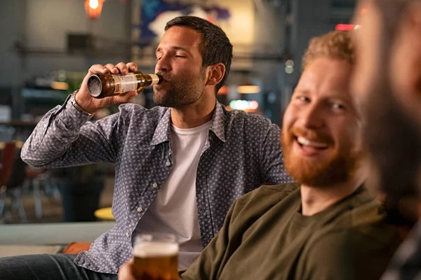 Человек с друзьями пьет бутылку пива — стоковое фото
