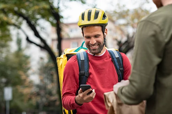 Liefermann überprüft Essensbestellung mit Smartphone — Stockfoto