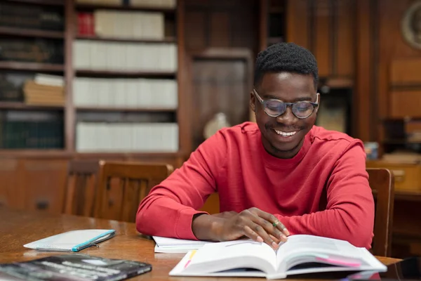 Щасливий студент університету читає в бібліотеці — стокове фото