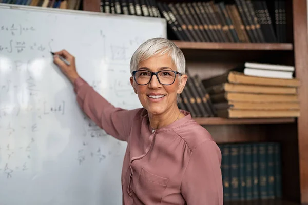 Mature teacher writing on whiteboard