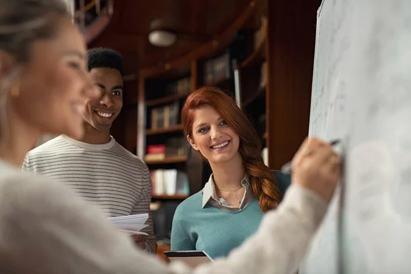 Studenti che guardano compagno di classe risolvere matematica sulla lavagna — Foto Stock