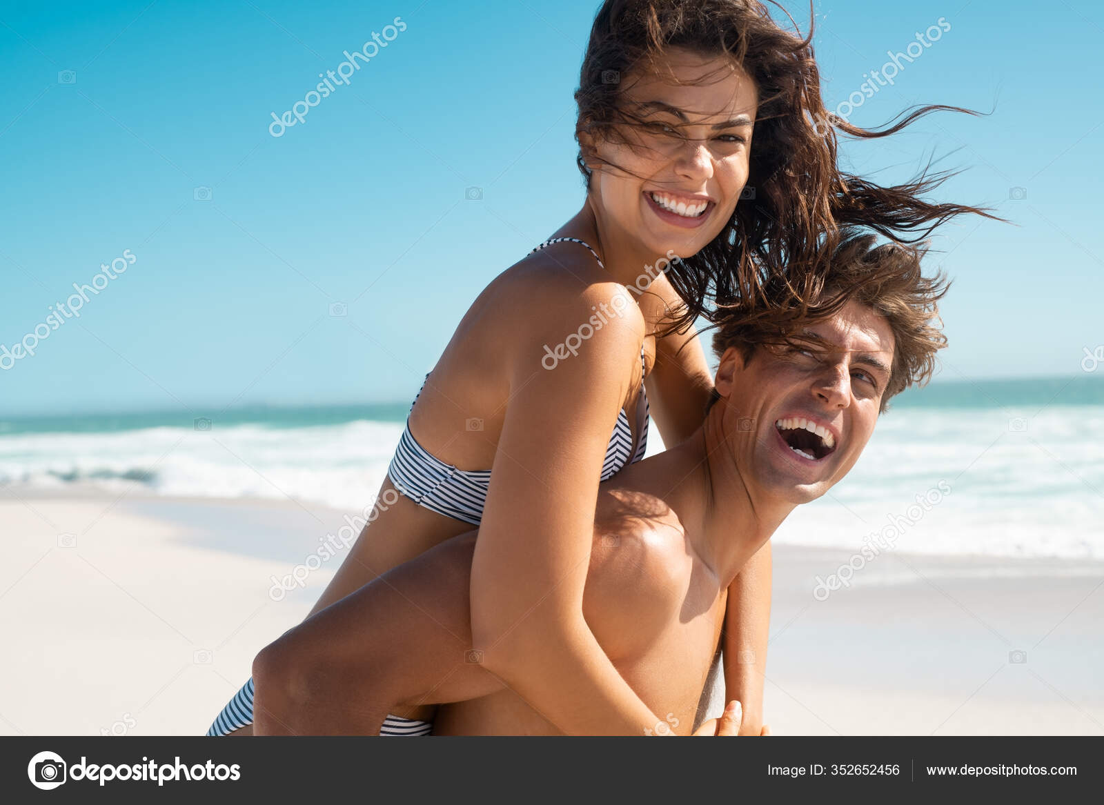 Cheerful woman holding on to boyfriends head while having piggyback ride  stock photo