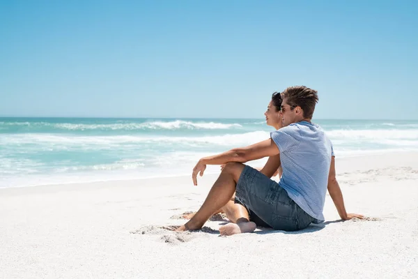 这对年轻夫妇坐在沙滩上 望着地平线 思前想后 快乐的男人和美丽的女人在海上享受浪漫的假期 这对有识之士在海滩上放松 凝视着大海 复制空间 — 图库照片