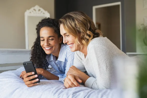 Веселые Многонациональные Подруги Делают Покупки Интернете Лежа Кровати Используя Смартфон — стоковое фото