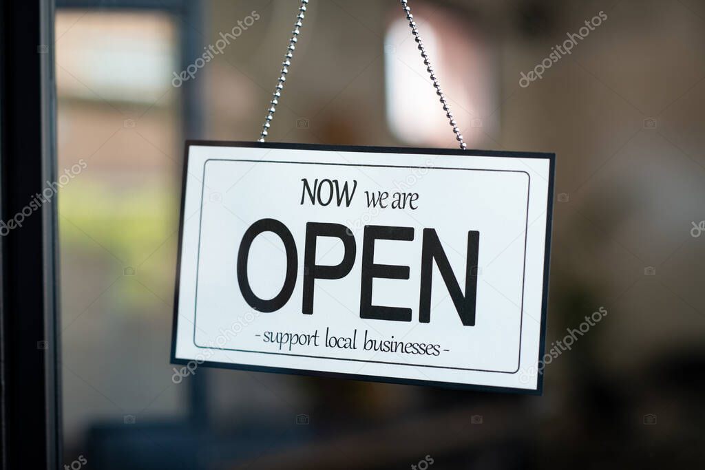 Reopening of a small business activity after the covid-19 emergency, ended the lockdown and quarantine. A business sign that says now we are open support local businesses on cafe or restaurant hang on door at entrance. Close up of open sign on the wi