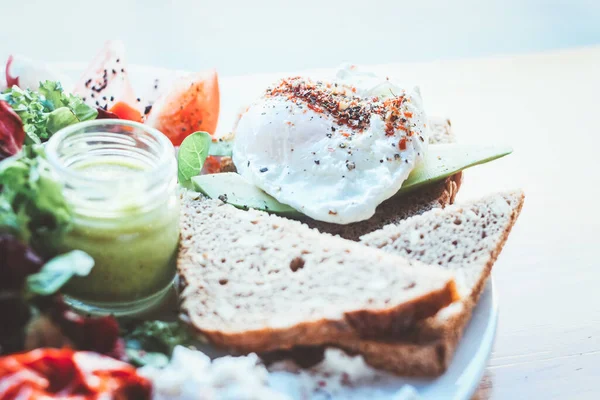 En iyi kahvaltı. Bir tabak haşlanmış yumurta, tost, avokado, domates, salata, yeşil sos..