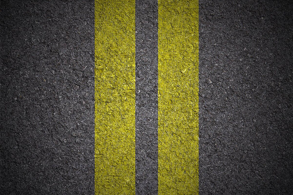 yellow double lines on asphalt background - close up