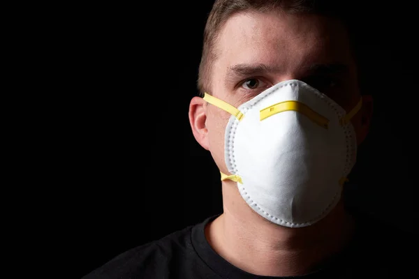 Genç adam karanlık atmosferde koruyucu bir maske takıyor.