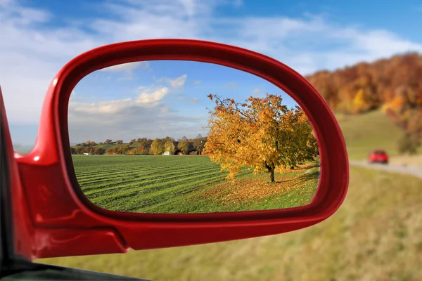 Paesaggio nello specchio retrovisore di un'auto rossa - serie autunnale — Foto Stock