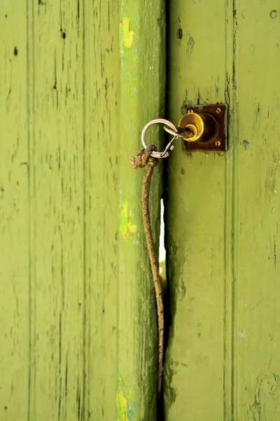 Sleutel met een bandje op een groene deur — Stockfoto
