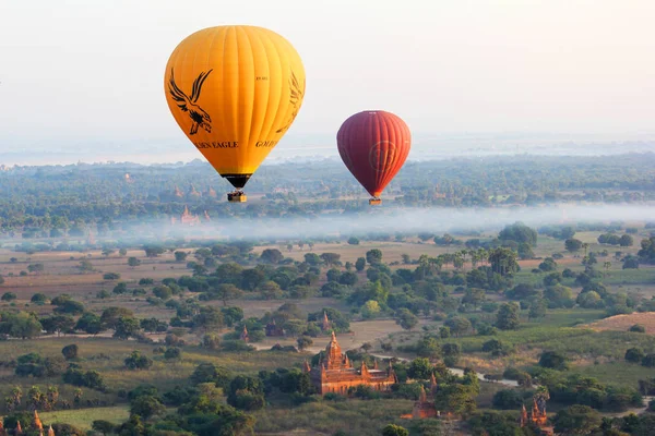 Heißluftballons fliegen an einem nebligen Morgen über der Ebene von Bagan, Myanmar — Stockfoto