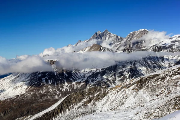 Alpen sneeuw bergen met wolken en mist — Stockfoto