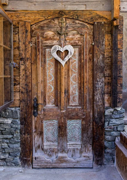 A rustic wooden door with hanging heart shape deco — Stock Photo, Image