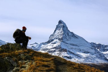 Arka planda Matterhorn zirvesi ile yürüyüş yaparken dinlenen genç bir yürüyüşçü. Matterhorn İsviçre Alplerinde bir cazibedir..