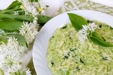 Ramsonlar (yaban sarımsaklı pırasa) parmesan peynirli risotto, taze Ramson yaprakları ve çiçeklerle servis edilir.
