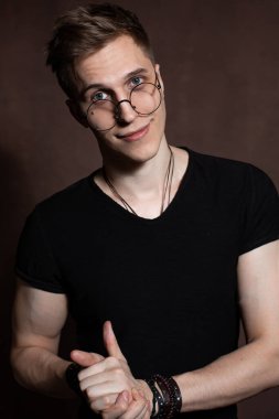 Handsome man in round glasses, a black t-shirt with bracelets