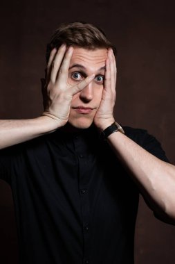 A man in round glasses and a black shirt is grimacing