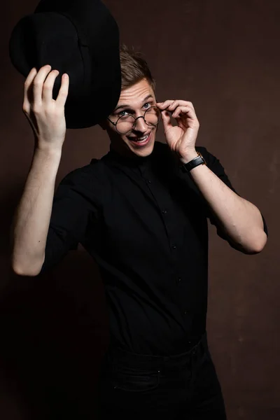 Homem de óculos redondos e camisa preta com chapéu — Fotografia de Stock