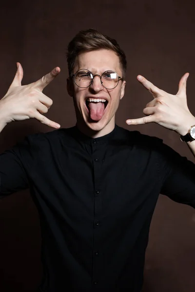 A man in round glasses and a black shirt is grimacing — ストック写真