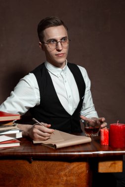 Yuvarlak gözlüklü bir adam kitap yazıyor.