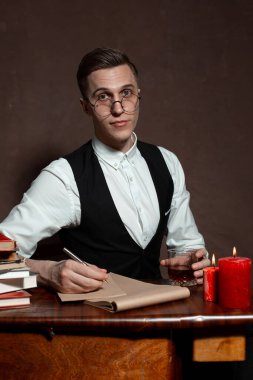 Yuvarlak gözlüklü bir adam kitap yazıyor.