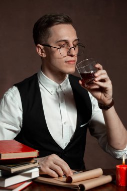 Yuvarlak gözlüklü bir adam kitap yazıyor.