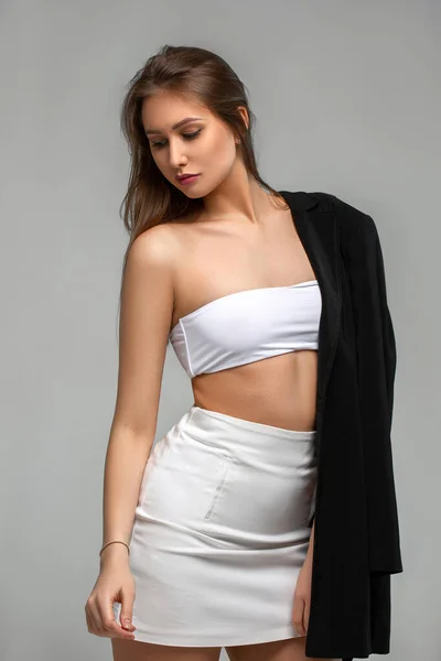 Meisje in wit met een zwart jasje op een lichte achtergrond — Stockfoto