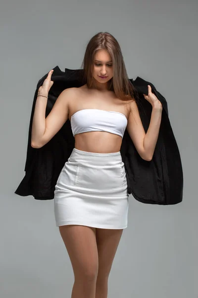 Menina em branco com uma jaqueta preta em um fundo claro — Fotografia de Stock