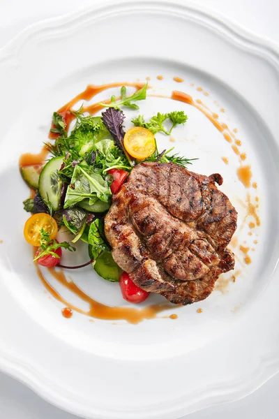 Schweinenackensteak mit gemischtem Salat auf weißem Restaurantteller — Stockfoto