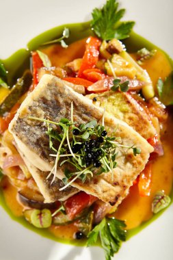 Beyaz tabakta sebzeli balık fileto.