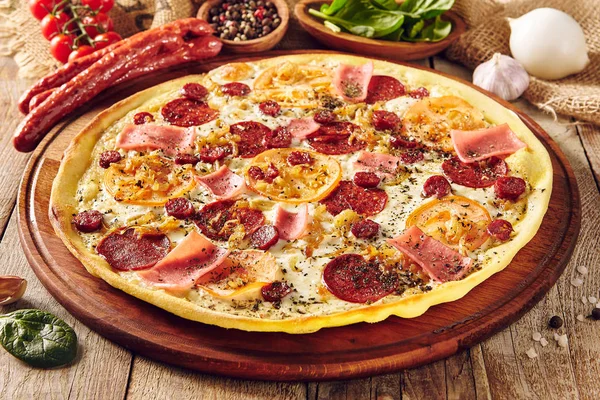 Meat and tomato pizza on wooden table close up