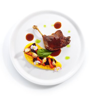 Genç sebzeler, çiçekler ve havuç kremalı kızarmış ördek bacağı.