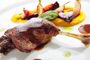 Genç sebzeler, çiçekler ve havuç kremalı kızarmış ördek bacağı.