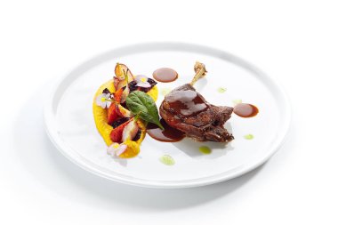 Genç sebzeler, çiçekler ve havuç kremalı kızarmış ördek bacağı.