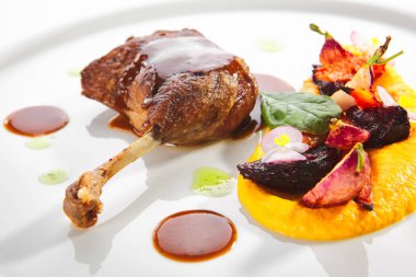 Genç sebzeler, çiçekler ve havuç kremalı kızarmış ördek bacağı.