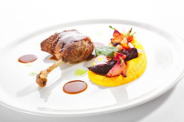 Genç sebzeler, çiçekler ve havuç kremalı kızarmış ördek bacağı.