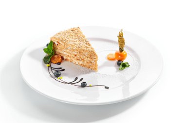 Bir parça Napolyon keki. Kremalı vanilyalı tatlı tabakta. Naneli ve yaban mersinli lezzetli hamur işi. Beyaz arka planda katmanlı fırında turta. Tatlı yemek sunumu