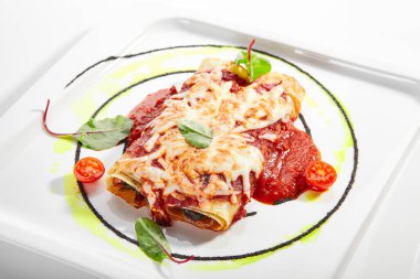 Dorblu peynirli ve domates soslu sebzeli cannelloni. Aromatik ıspanakla servis edilen rulo lazanya. Geleneksel Katalan mutfağı. Lezzetli Akdeniz yemeği yakın çekim görüntüsü. İtalyan yemeği