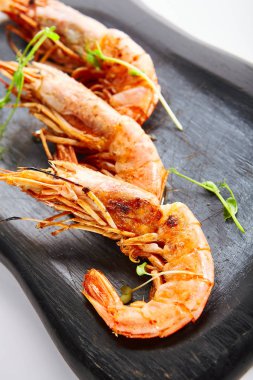 Arjantin karidesleri. Siyah tabakta kırmızı karides servis ettim. Şifalı bitkilerle süslenmiş deniz ürünleri restoranı yemekleri. Deniz lezzeti, Akdeniz gurmesi yemeği. Haşlanmış karides.