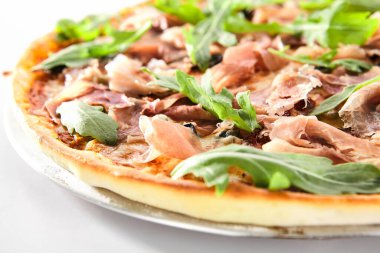 Geleneksel İtalyan pizzası, kurutulmuş domates, kapari, prosciutto, roka ve mozzarella peyniri izole edilmiş. Lezzetli İtalyan ekmeği, ince dilimlenmiş jambon, sıcak lezzetli fast food yakın plan.