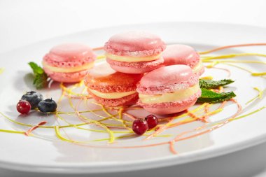 Beyaz tabakta makarna. Fransız tatlısı. Tereyağlı sandviçli kurabiye. Kremalı lezzetli bisküviler ve yanında pembe gıda boyası. Tatlı şekerleme, fırın