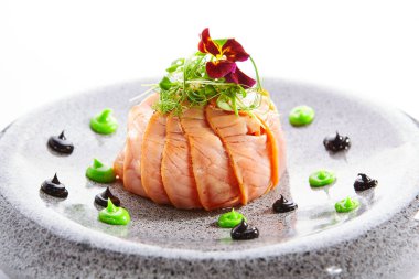 Somonlu olivier salatası. Dilimlenmiş yeşil balık yemeği. Menekşe çiçeğiyle süslenmiş lezzetli deniz ürünleri. Tabaklara yakın çekim mutfağı. Restoran yemeği, zarif yemek kompozisyonu.