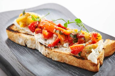 Fırında biberli nefis bruschetta. Yakın görüş. Peynirli ve sebzeli kızarmış ekmek. Ahşap tepside yeşillik bulunan geleneksel İtalyan pancarı. Avrupa mutfağı, besin bileşimi