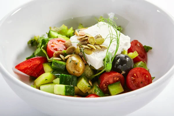 白いボウルにギリシャのサラダ 新鮮な野菜やフェタチーズをスライス 伝統的なギリシャ料理を提供します 生のトマトをカット プレートにオリーブオイルとキュウリ レストランフード部分が閉まります — ストック写真