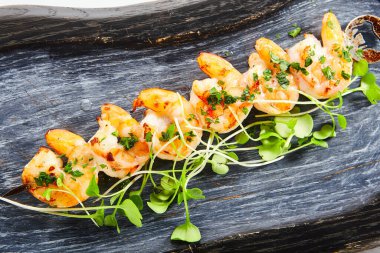 Karides kebabı manzaralı. Yeşillikli lezzetli deniz ürünleri. Ahşap tepside bahçe tereli kavrulmuş karides. Mutfak sunumu, yemek kompozisyonu. Lezzetli restoran yemeği, haute cuisine