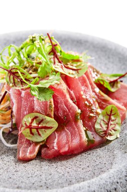 Tataki ton balığı yakın çekim görüntüsü. Geleneksel Japon mutfağı metodu. Tabakta lezzetli balıklar var. Yeşillik ve baharatlı dilimlenmiş deniz ürünleri. Asya mutfağı, yemek kompozisyonu. Restoran yemeği.