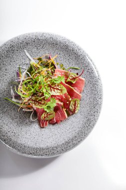 Tataki ton balığı yan görüntüsü. Geleneksel Japon mutfağı metodu. Tabakta lezzetli balıklar var. Yeşillik ve baharatlı dilimlenmiş deniz ürünleri. Asya mutfağı, yemek kompozisyonu. Restoran yemeği.