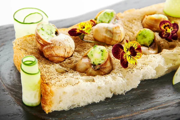 具有大蒜和奶酪侧面视图的蜗牛 美味的意式意式沙司 木盘上的美食佳肴 美味佳肴配上紫罗兰在面包上食用 法国食品展示 烹饪菜单 — 图库照片