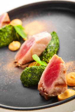 Haşlanmış ıspanaklı ton balığı filetosu. Baharatlı ve tabağında yeşillik olan lezzetli deniz ürünleri. Balık ve soslu lezzetli bir yemek. Haute cuisine, yemek sunumu. Geleneksel tarif