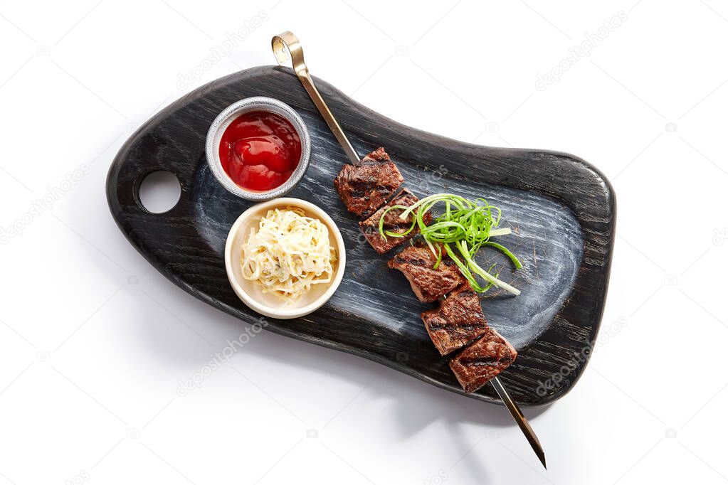 Marbled beef skewer top view. Delicious kebab with sauce and noodles on wooden tray. Grilled meat with tasty garnish. Spicy meal with onion. Restaraunt dish, roasted food composition